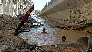 Rodeados por la destrucción, estos niños juegan en un cráter producido por una bomba en la ciudad siria de Alepo.