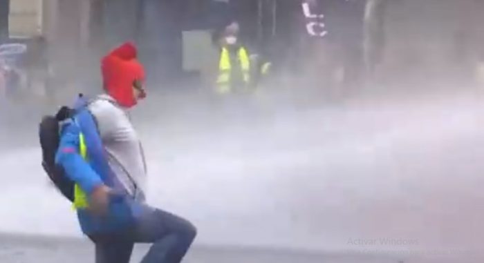 Manifestante en París pone el pecho al agua de carros policiales