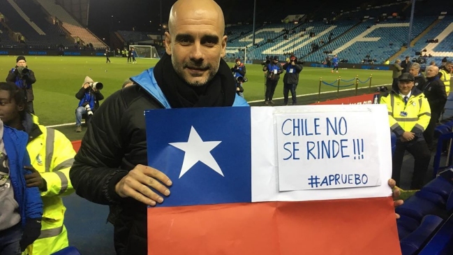 Pep Guardiola posa junto a una bandera con el mensaje: «Chile no se rinde, apruebo»